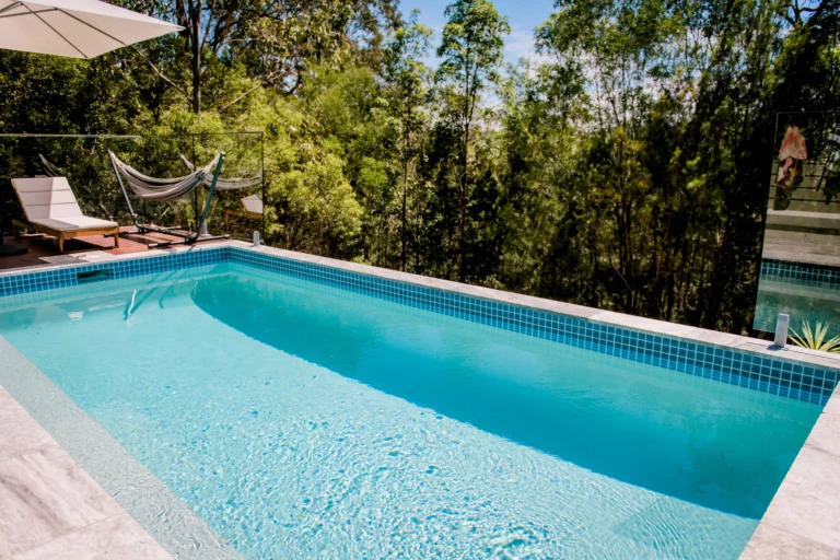 A serene pool with a hammock and a lounge chair, expertly crafted by a Brisbane pool contractor